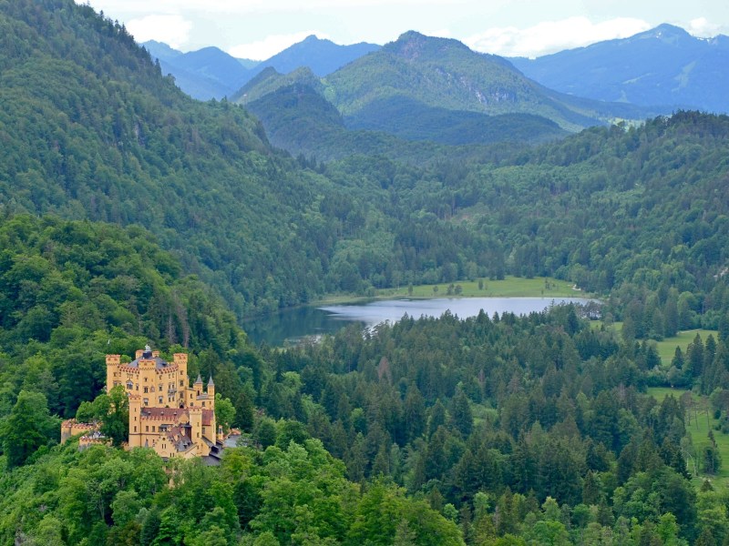 View of Neuschwanstein Castle, a lake, trees and mountains